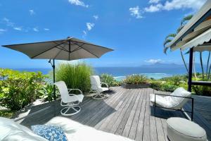 a wooden deck with chairs and an umbrella at Villa Tiare amazing view - private pool - 4 bedrooms- up to 7 pers in Punaauia