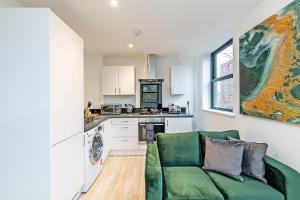 a living room with a green couch and a kitchen at Winckley House Serviced Apartments in Preston in Preston