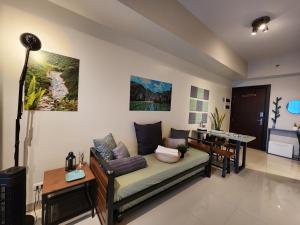 uma sala de estar com um sofá e uma mesa em 4 Pax Cozy Uptown Mall Unit with Balcony and Parking em Manila