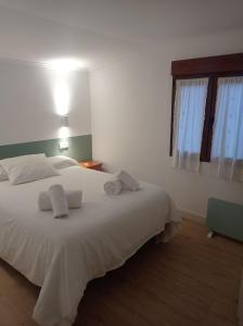 ein Schlafzimmer mit einem weißen Bett mit zwei Handtüchern darauf in der Unterkunft La casina de Pichi in Caravia