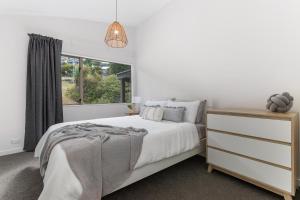 a white bedroom with a bed and a window at Spacious relaxing home in Queenstown