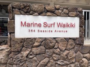 a sign for a marmite surfwalkwalk sign on a stone wall at Marine Surf in Honolulu