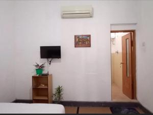 a bedroom with a white wall with a television and a door at Brak Homestay in Sukobumi