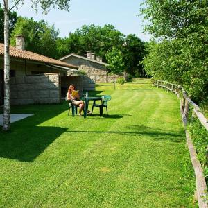 Una donna seduta al tavolo da picnic sull'erba di Bungalows - Serra do Gerês a Campo do Gerês