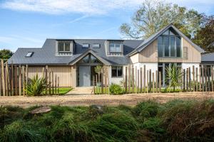 a house with a wooden fence in front of it at The Salt House - Luxury Home with Pool & Hot Tub in Chichester