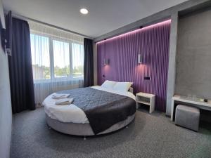 sypialnia z dużym łóżkiem i fioletową ścianą w obiekcie Art Hotel Palma w Lwowie