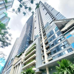 um edifício alto com palmeiras em frente em 4 Pax Cozy Uptown Mall Unit with Balcony and Parking em Manila