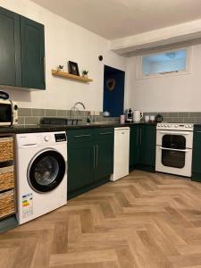 a kitchen with green cabinets and a washer and dryer at 'Downtown' @ Terracotta Court in Bradford on Avon