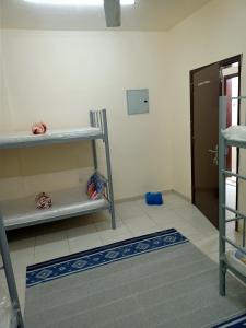 um quarto com uma cadeira, uma prateleira e uma porta em SmSma BedSpace Hostel em Ajman
