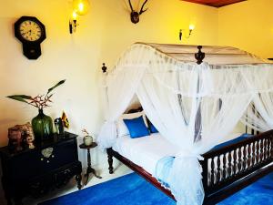 a bedroom with a canopy bed with a clock on the wall at Sriyan Villa in Beruwala