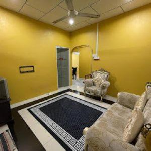 ein Wohnzimmer mit einem Sofa und einer gelben Wand in der Unterkunft Alyaa Homestay in Gua Musang