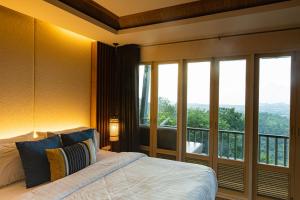 Phuket View Coffee and Resort في تشالونج: غرفة نوم بسرير ونافذة كبيرة