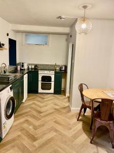 uma cozinha com armários verdes, uma mesa e um fogão em 'Downtown' @ Terracotta Court em Bradford on Avon
