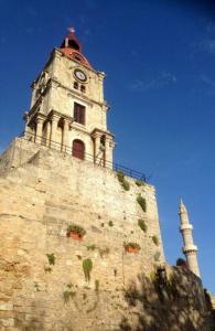 un bâtiment avec une tour d'horloge en haut dans l'établissement The Knight and the Pomegranate - Luxury Medieval Villa, à Rhodes