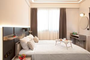 Un dormitorio con una gran cama blanca y una mesa en Pearl SeaBreeze Suites en Rethymno