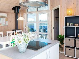 a kitchen with a table with a vase of flowers at 6 person holiday home in Hemmet in Falen