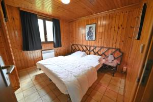 a bedroom with a large bed in a wooden room at La Tanière in Noiseux