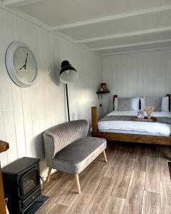 1 dormitorio con 1 cama y reloj en la pared en Trethowels Grey Hidden hut en St Austell