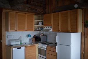 cocina con nevera blanca y armarios de madera en Villa Sukka en Kuusamo