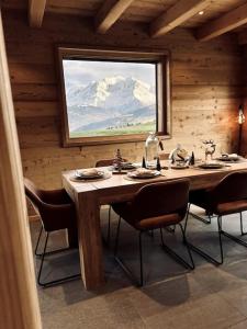 a dining room with a table with chairs and a window at Chalet Vue Mont-Blanc imprenable in Combloux