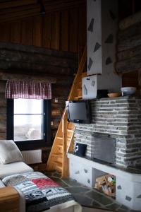 Habitación con chimenea de piedra y TV en la pared. en Villa Sukka en Kuusamo