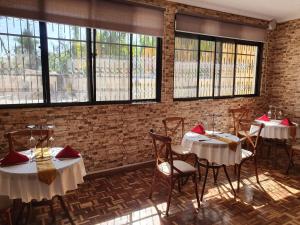a dining room with tables and chairs and windows at The VIP Luxury Lounge Hotel in Kisumu