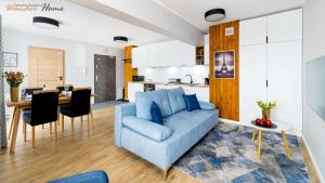 a living room with a blue couch and a kitchen at Wonder Home - Apartamenty Blisko Gór w zielonej części Karpacza - przy przy stoku i szlakach turystycznych in Karpacz