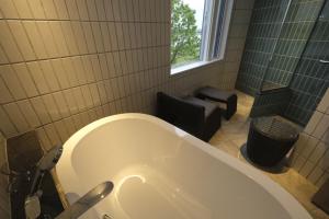 a bathroom with a tub and a chair and a window at Kangetsuen in Otofuke