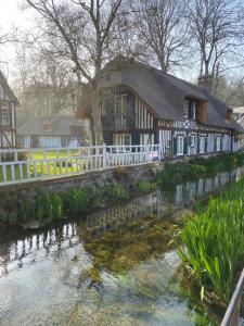 una casa con una cerca blanca junto a un río en Les gîtes du château du cèdre, en Manneville-ès-Plains