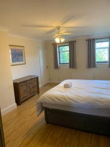 a bedroom with a bed and a dresser and two windows at Super King Bed Suite, Executive office, fast WiFi, free parking in St. Ives