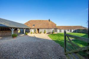 a barn with a fence in front of a yard at Luxury, countryside barn conversion with Hot tub in Kent