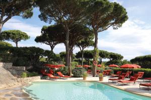 una piscina con sedie, ombrelloni e alberi di Hôtel Villa Marie Saint Tropez a Saint-Tropez