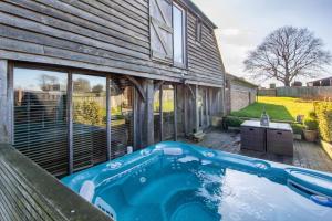 a swimming pool in front of a house at Luxury, countryside barn conversion with Hot tub in Kent
