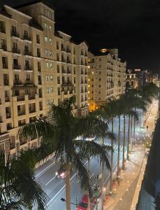 uma rua da cidade com palmeiras e edifícios à noite em 2F Newport Condotel em Manila