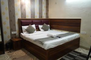 a bed with a wooden headboard in a room at Hotel Quadis - Noida sec 15 in Noida