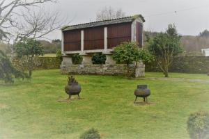 dwa duże garnki siedzące w trawie przed domem w obiekcie CASA DE ALDEA VAL DOS SOÑOS w mieście Lugo