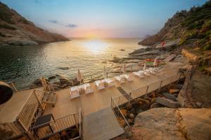 アルバタックスにあるArbatax Park Resort - Borgo Cala Morescaのビーチの景色を望む客室で、椅子、水辺が備わります。