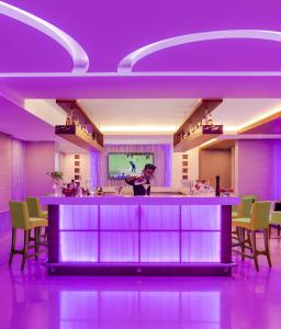 a woman standing at a bar in a room with purple lighting at Vivanta Thiruvananthapuram in Trivandrum