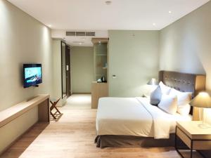 ein Hotelzimmer mit einem Bett und einem TV in der Unterkunft AONE Hotel in Jakarta