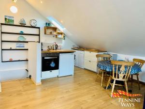 a kitchen with white cabinets and a table and chairs at The Boat House, Northumberland Village Location in Brampton