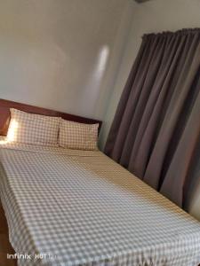 a bedroom with a bed with a checkered blanket and a window at Sealey's Inn in Sipalay