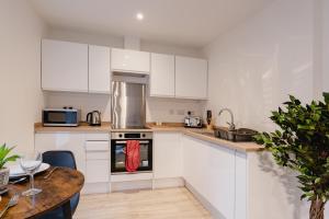 uma cozinha com armários brancos e uma mesa de madeira em Prescott Court Serviced Apartments em Halifax