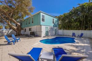 a house with a swimming pool and blue chairs at Coquina Cottage B home in Anna Maria