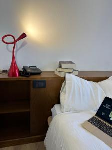 ein Bett mit einer roten Lampe und einem Laptop darauf in der Unterkunft Hotel Alle Tre Baite in Santa Caterina Valfurva