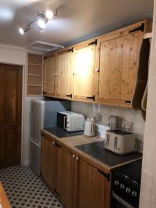 uma cozinha com armários de madeira e uma bancada em Coronation Place em Troed-y-rhiw