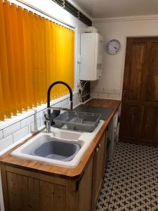 uma cozinha com um lavatório e uma janela amarela em Coronation Place em Troed-y-rhiw
