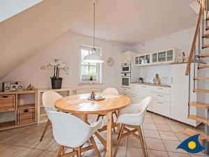 a kitchen with a wooden table and white chairs at Fraeulein Loddin Whg_ Hugo in Kölpinsee