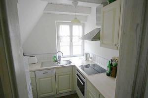 a white kitchen with a sink and a window at Haus am Achterwasser Whg "Klabautermann" in Ueckeritz