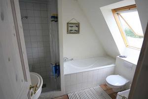 a bathroom with a tub and a toilet and a sink at Haus am Achterwasser Whg "Klabautermann" in Ueckeritz