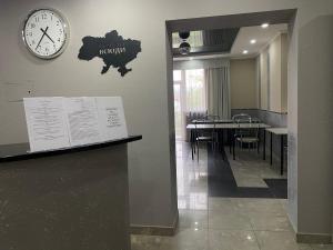 une salle à manger avec une horloge et une table avec des chaises dans l'établissement Готель «У Батька», à Trouskavets